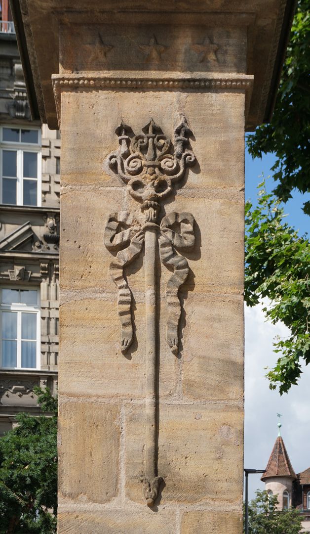 Pumpbrunnen Relief mit Dreizack als Attribut des Neptun und Schleife