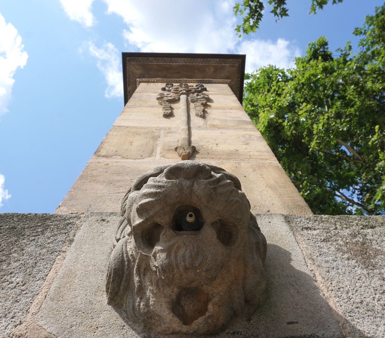 Pumpbrunnen Löwenkopf und Brunnenstock aus der Froschperspektive