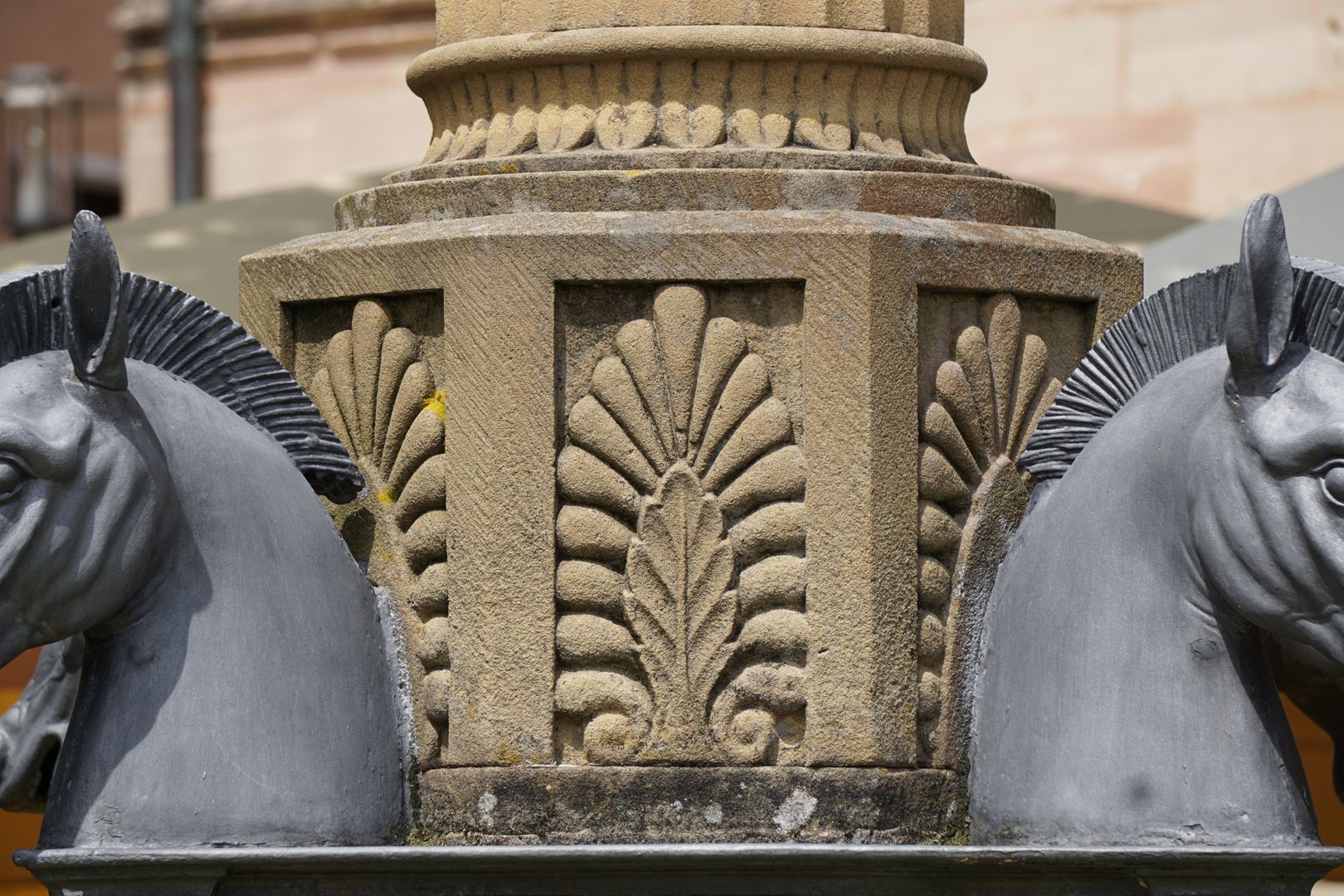 Pferdebrunnen Achteckiges Säulenpostament mit stilisierten Akanthusblättern zwischen Pferdeköpfen. Darüber Basis mit Blattwelle und dem Anfang der kannelierten Säule.