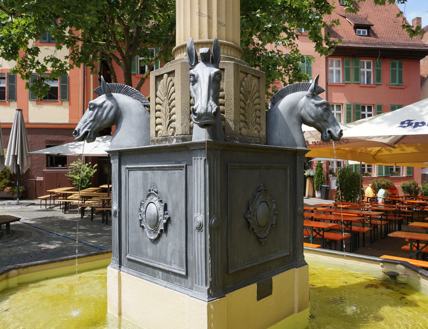 Pferdebrunnen Das achteckige Säulenpostament mit stilisierten Akanthusblättern wird von 4 Pferdeköpfen eingefasst.